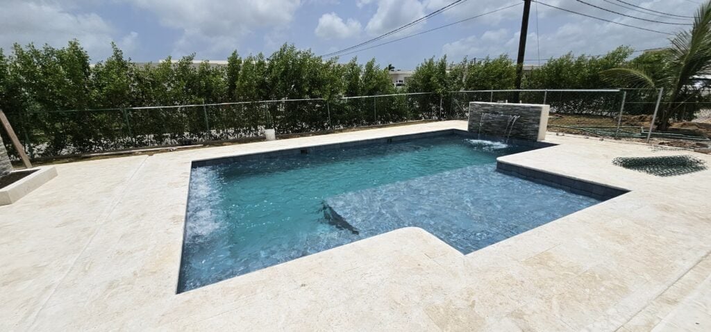 Vista lateral de la piscina en Ciudad La Palma, con muro decorativo y terraza.
