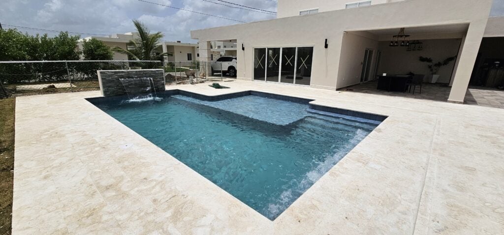 Piscina de Ciudad La Palma junto a la terraza y los ventanales de la vivienda.