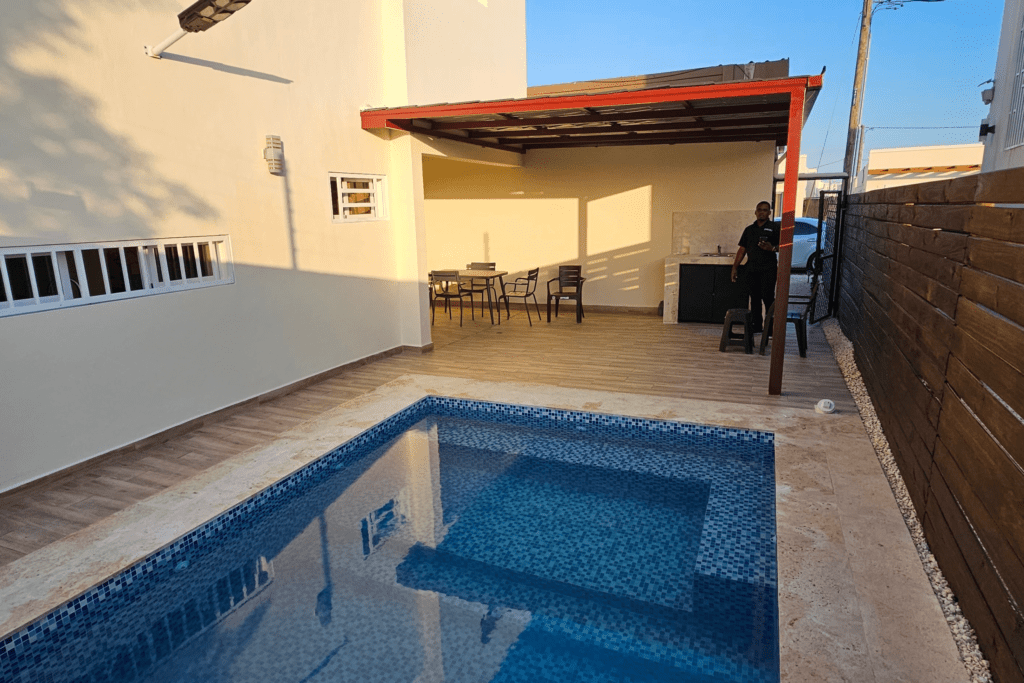 Piscina y terraza en Ciudad del Sol, con pérgola, revestimiento azul y cerramiento de madera.