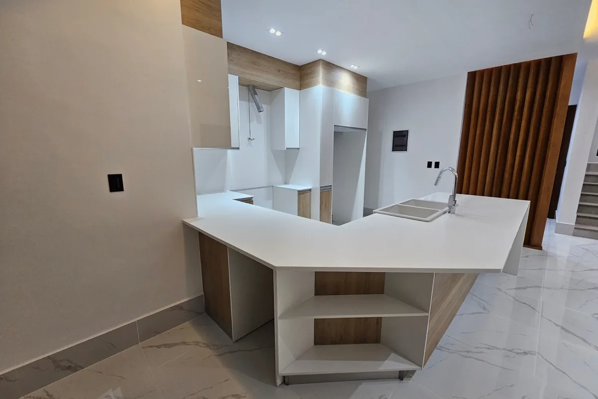 Cocina de Nain Luxury, con encimera blanca y panel de listones de madera.