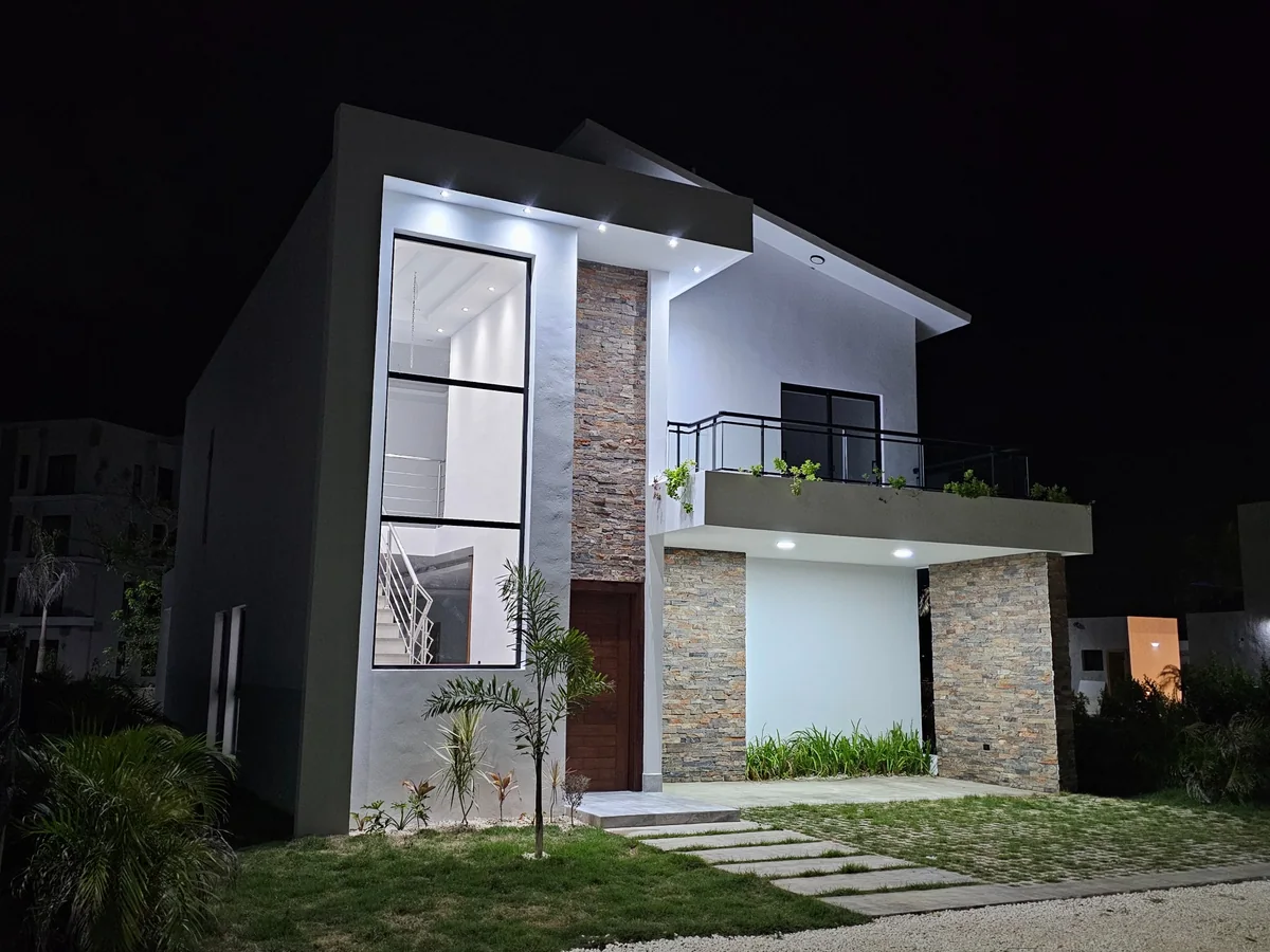 Fachada de Nain Luxury iluminada por la noche, con ventanal vertical y balcón.