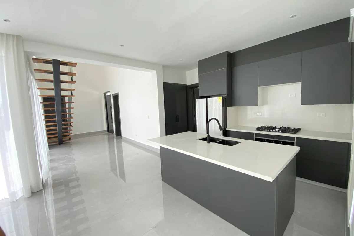Cocina de la villa de 232 m², con muebles grises, isla blanca y escalera al fondo.